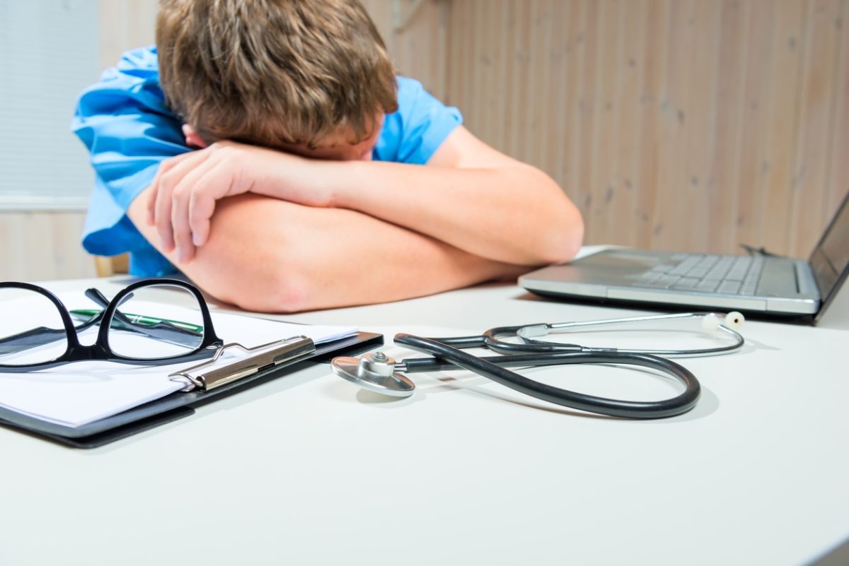 Young male nurse asleep at desk.