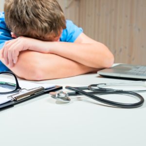 Young male nurse asleep at desk.