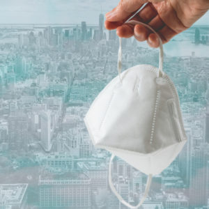 Mask against urban skyline. COVID-19 transition from pandemic to endemic.