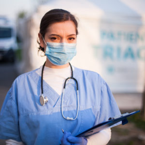 Crisis standards of care: Nurse in front of outdoor triage area.