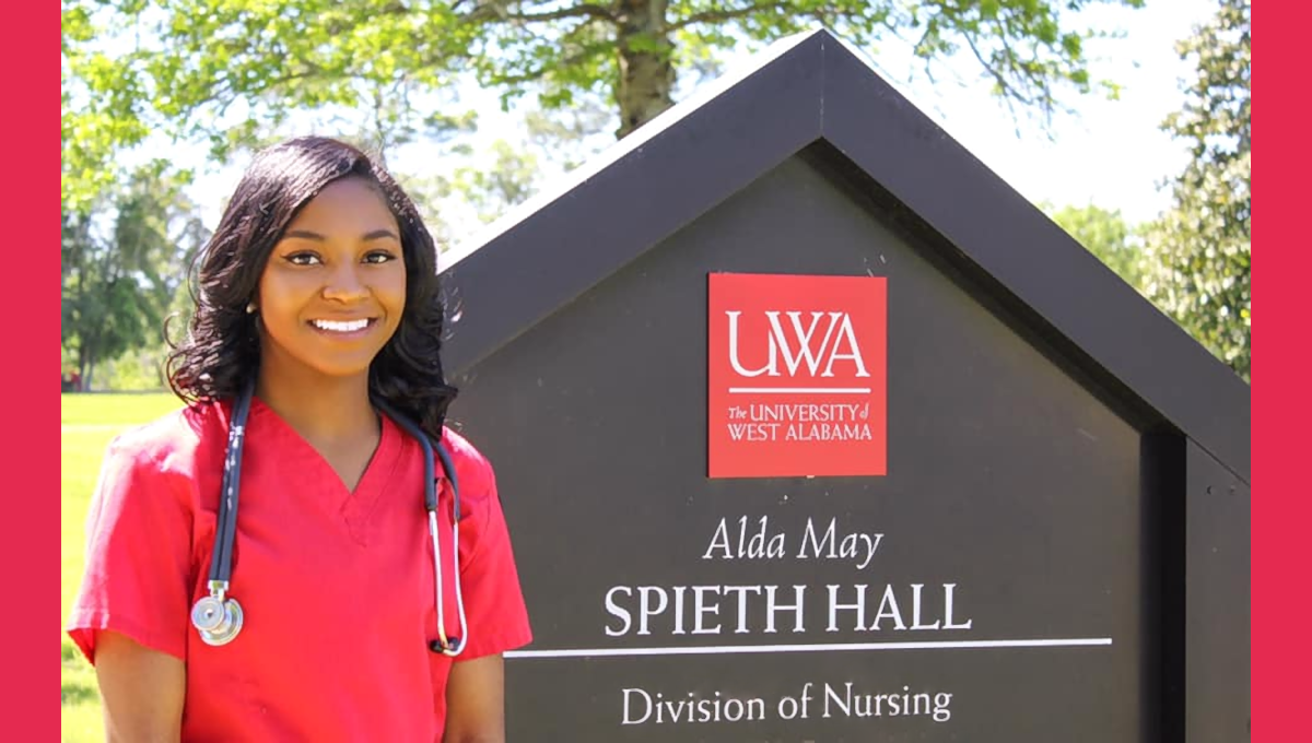 Student stands beside University of West Alabama Nursing Program sign.