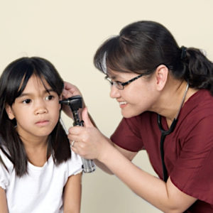 A family nurse practitioner or NP examines a child's ear.