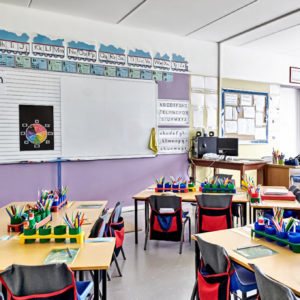 Empty Classroom In Elementary School With Whiteboard And Desks.