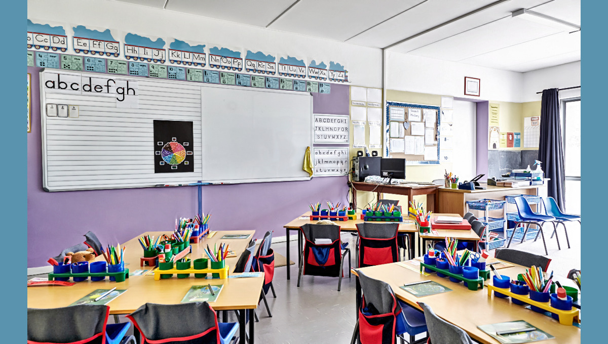 Empty Classroom In Elementary School With Whiteboard And Desks.
