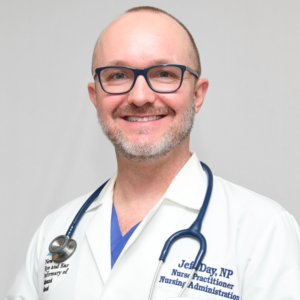 LGBTQIA+ nurse JEff Day in a white medical coat and with a stethoscope around his neck