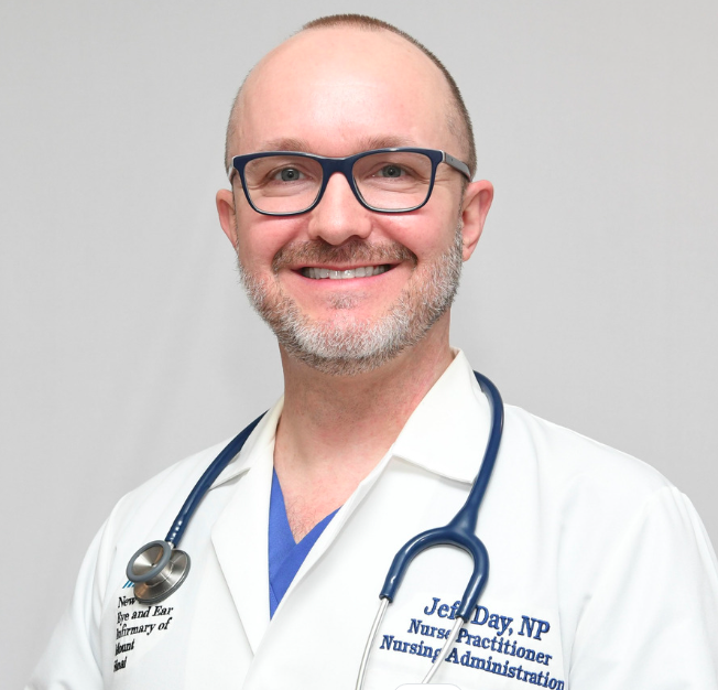 LGBTQIA+ nurse JEff Day in a white medical coat and with a stethoscope around his neck