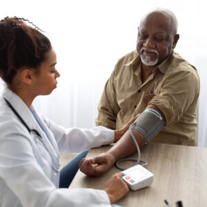 Black nurse checking measuring patient's pressure.