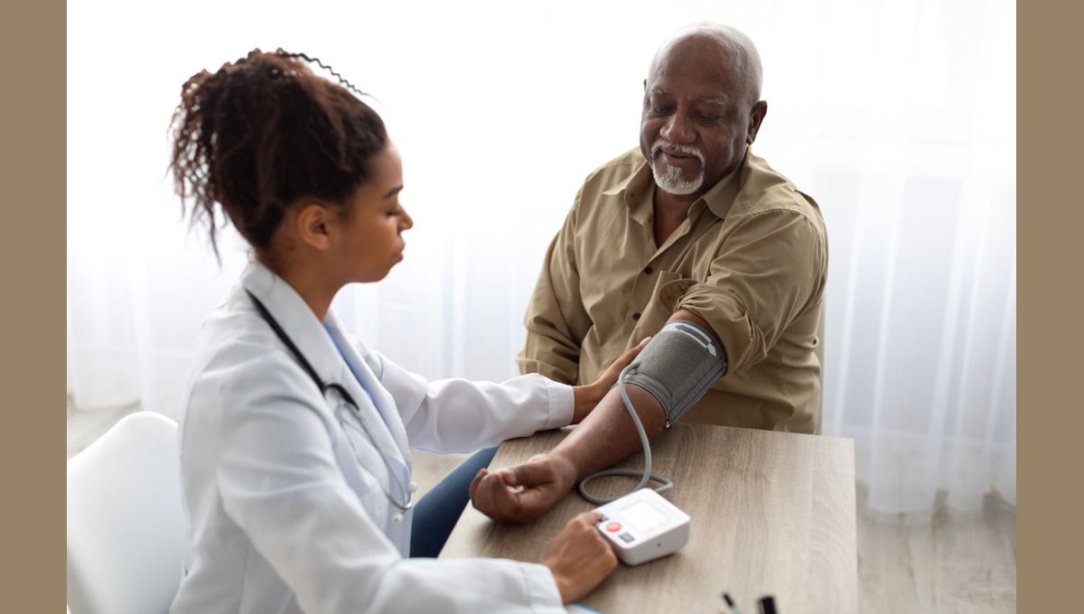 Black nurse checking measuring patient's pressure.