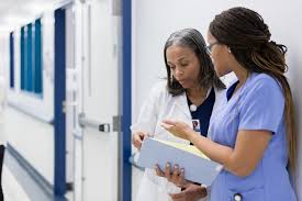 work friendships whown with two nurses talking in a hallway and looking at a medical chart