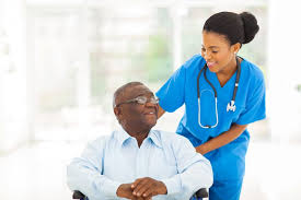 a standing female nursing assistant helping a sitting male patient