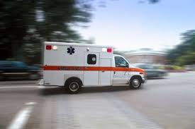 transport nurses work in a white ambulance with a red stripe moving on a road