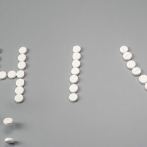 White pills forming the word 'HIV' on a grey background, symbolizing treatment.