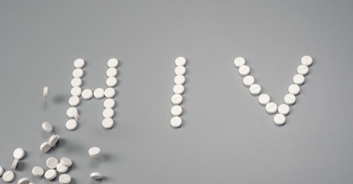 White pills forming the word 'HIV' on a grey background, symbolizing treatment.