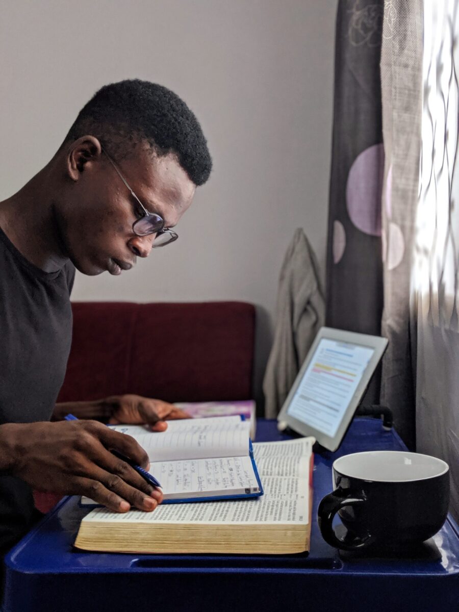 a young male at a table or desk with books and a coffee cup nearby studying to develop good study skills and study habits