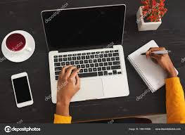 two hands over a laptop and a paper pad working on written communication